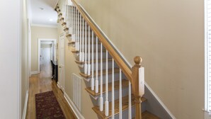 A staircase with wooden steps and white balusters, leading to a landing with a door.