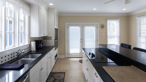 A kitchen with white cabinets, a black countertop, and a wooden cutting board.
