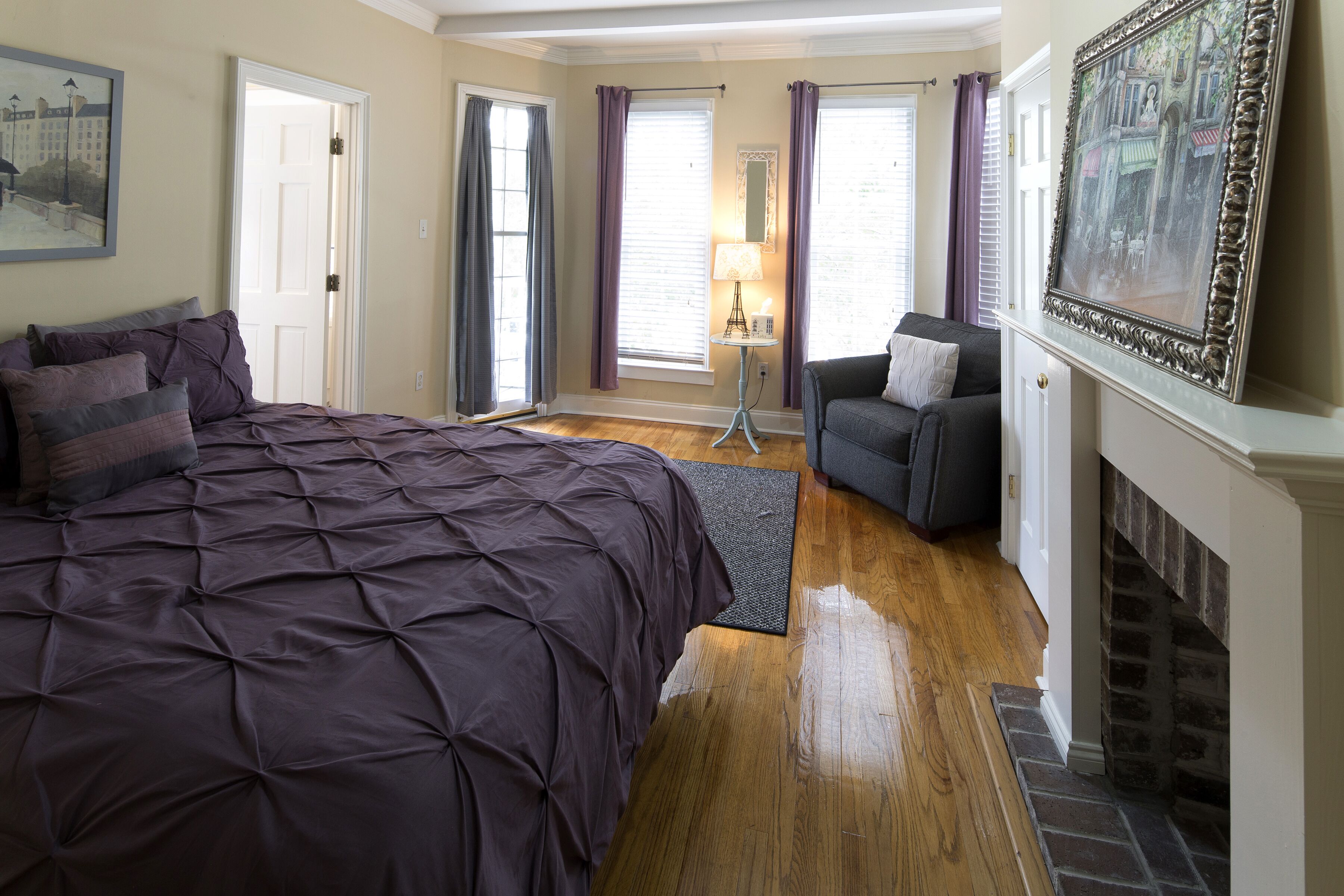 Une chambre avec un grand lit, un canapé, une cheminée et une vue sur l’extérieur par les fenêtres.