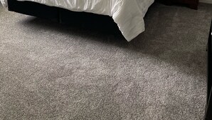 Ein Schlafzimmer mit einem großen Bett, zwei Nachttischen, einem Deckenventilator und einem Teppichboden.