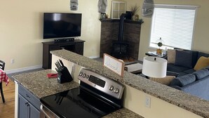 Eine moderne Küche mit Granit Arbeitsplatten, einem eingebauten Backofen und einem Herd. Es gibt einen Deckenventilator, einen Fernseher und einen Kamin aus Stein.