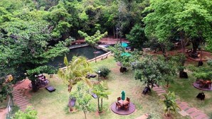 Un exuberante jardín con un estanque, rodeado de varias zonas de estar y árboles.