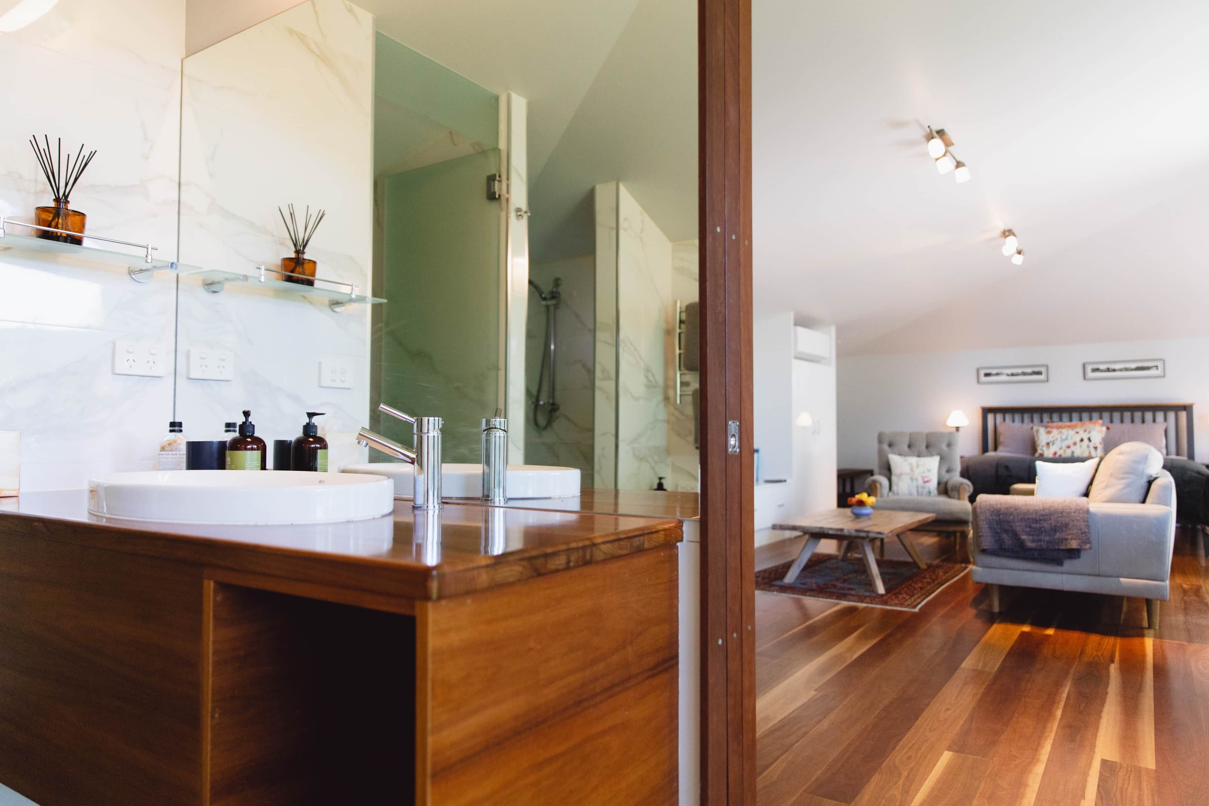 A modern bathroom with a wooden vanity, a large mirror, and a glass shower enclosure.
