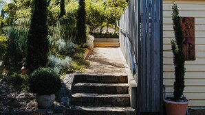 Un sendero que lleva a un edificio con muro de piedra y escalones.