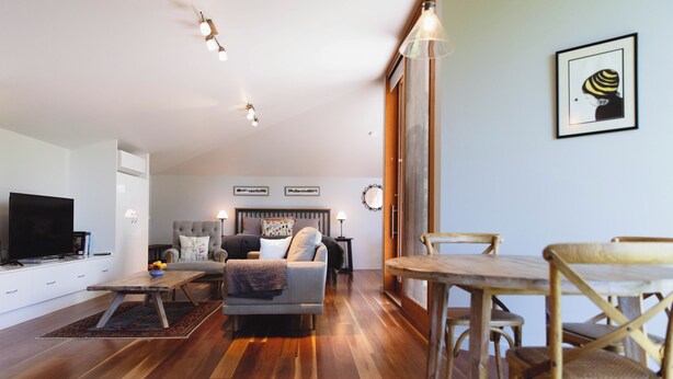 Una sala moderna con sofá, mesa de centro y mesa de comedor. Hay un televisor a la izquierda y una chimenea en el centro.