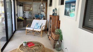 A cozy living area with a wicker chair, a round table with a book, and a wicker ottoman.