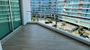 Un balcon donnant sur un immeuble moderne à plusieurs étages, avec un parking situé en contrebas.