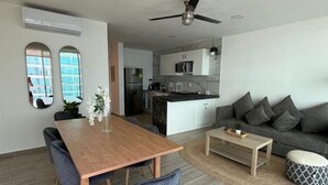 Un salon moderne avec une table à manger en bois, des chaises à revêtement gris, un canapé gris et une petite table basse.