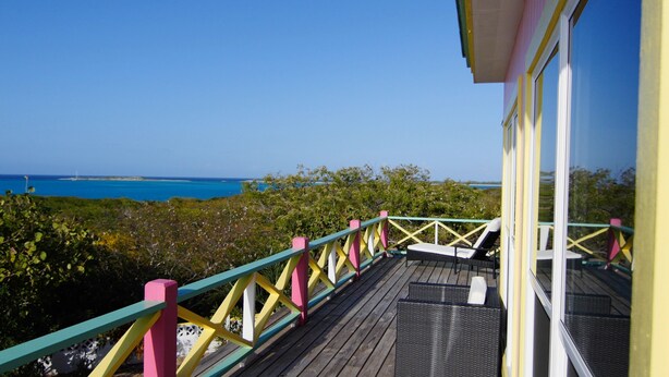 A wooden deck with colorful railings overlooking a coastal view. - Las Breezes 5 Bedroom Villa, With 1/2 Mile Private Beach On Hooper's Bay (George Town)