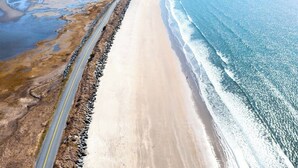 A coastal road with a beach on one side and a body of water on the other. - Island House Above Trees! 360° Oceanview, 4BR, Car-Accessible, Near Lunenburg   (La Have Island)