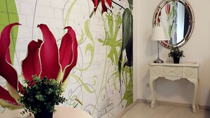 A room with a white table, a potted plant, a mirror, and a decorative wall with green and red accents. - Gorgeous quiet large townhouse on Budapest border (Budaörs)