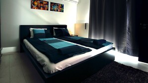 A double bed with a dark headboard, a bedside table with a lamp, and a window with curtains. - Gorgeous quiet large townhouse on Budapest border (Budaörs)