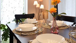 A dining table set with white plates, bowls, and glasses, a vase with orange flowers, and a lamp in the background. - Gorgeous quiet large townhouse on Budapest border (Budaörs)