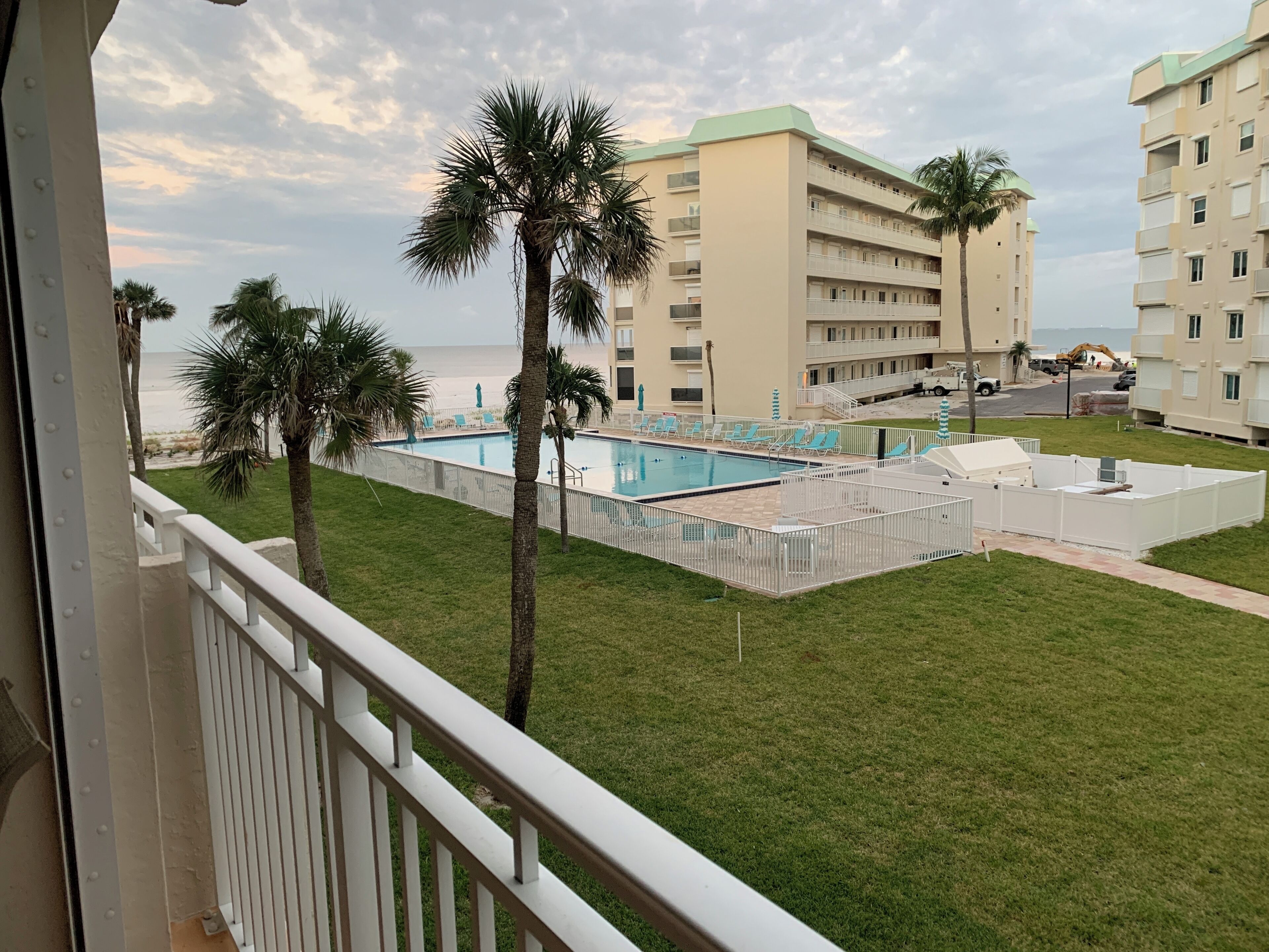 Ein Poolbereich mit Blick auf einen Strand und ein mehrgeschossiges Gebäude im Hintergrund.
