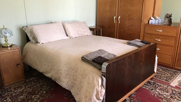 A bedroom with a bed, a nightstand, a dresser, and a rug.