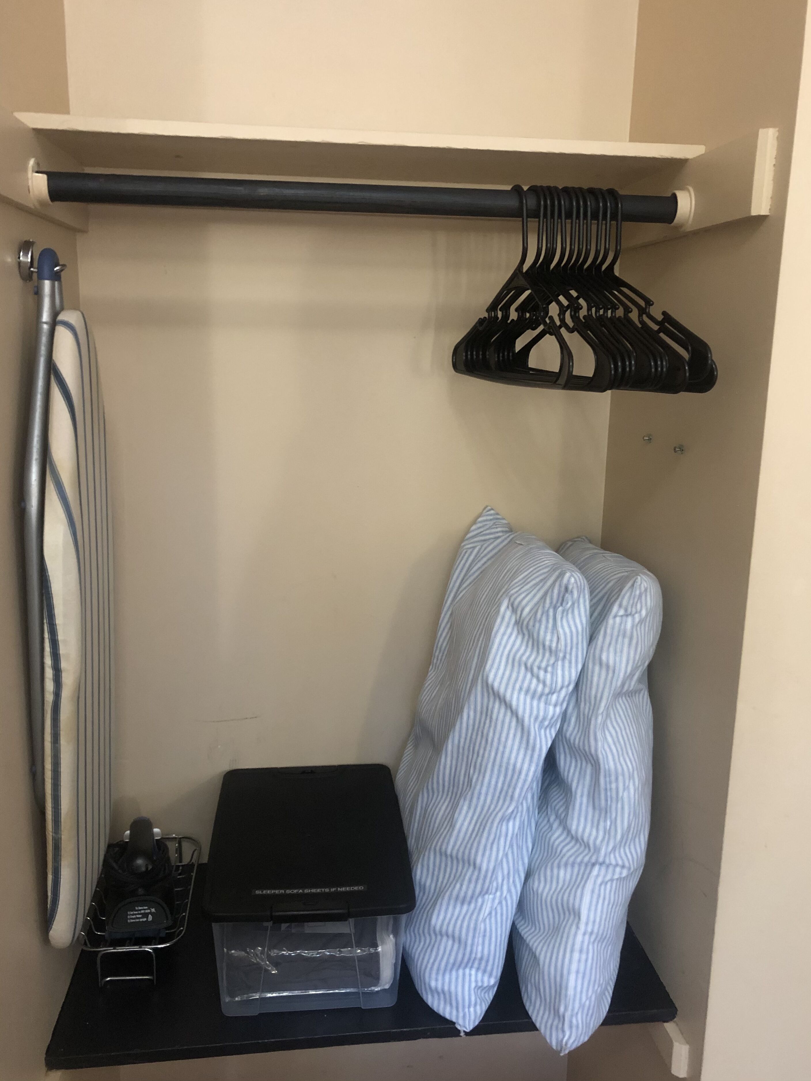 A closet with a hanging rod, a storage shelf, and a shoe rack.