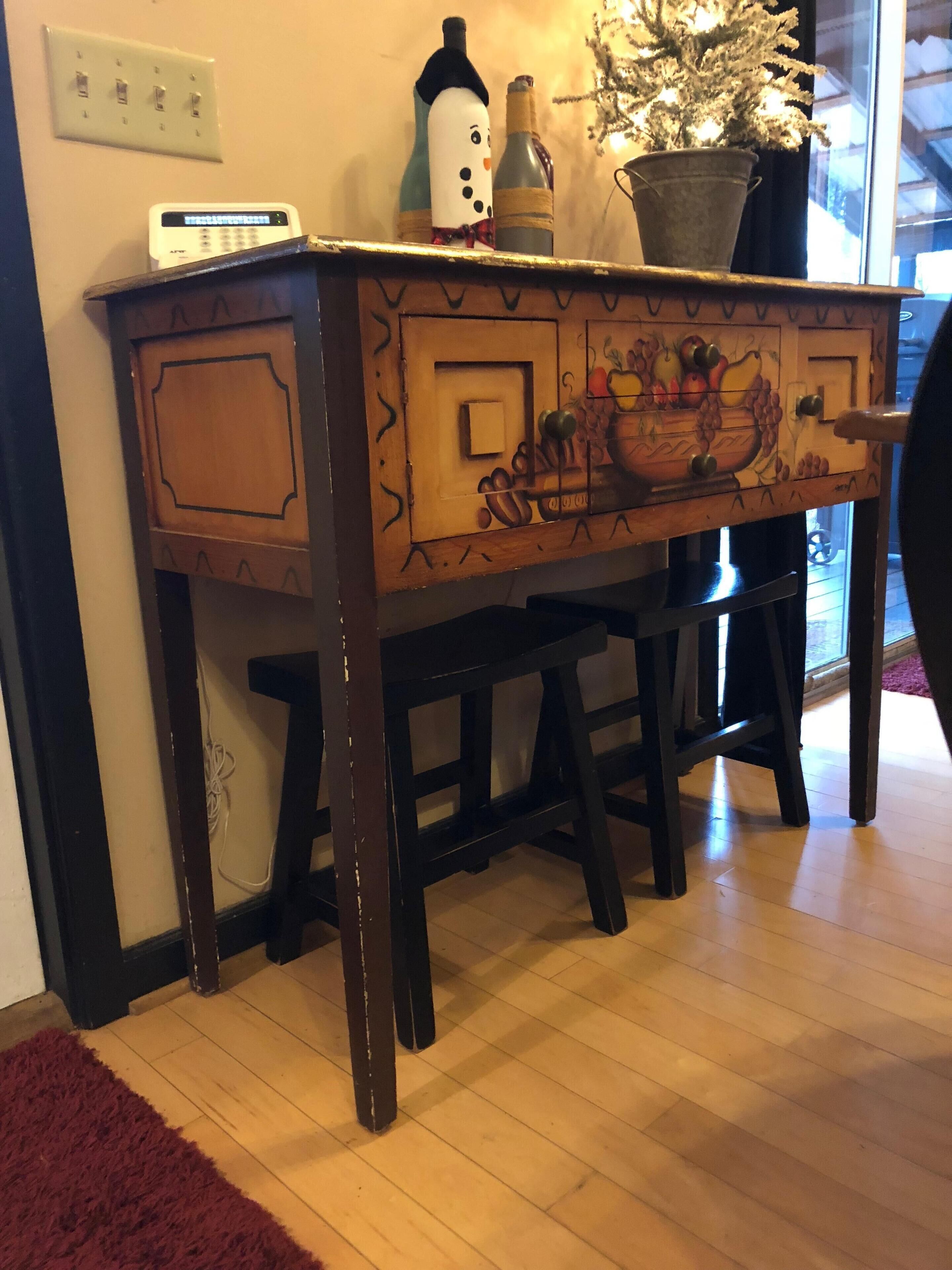 Een houten bureau met lades, een klein elektronisch apparaat en een potplant.