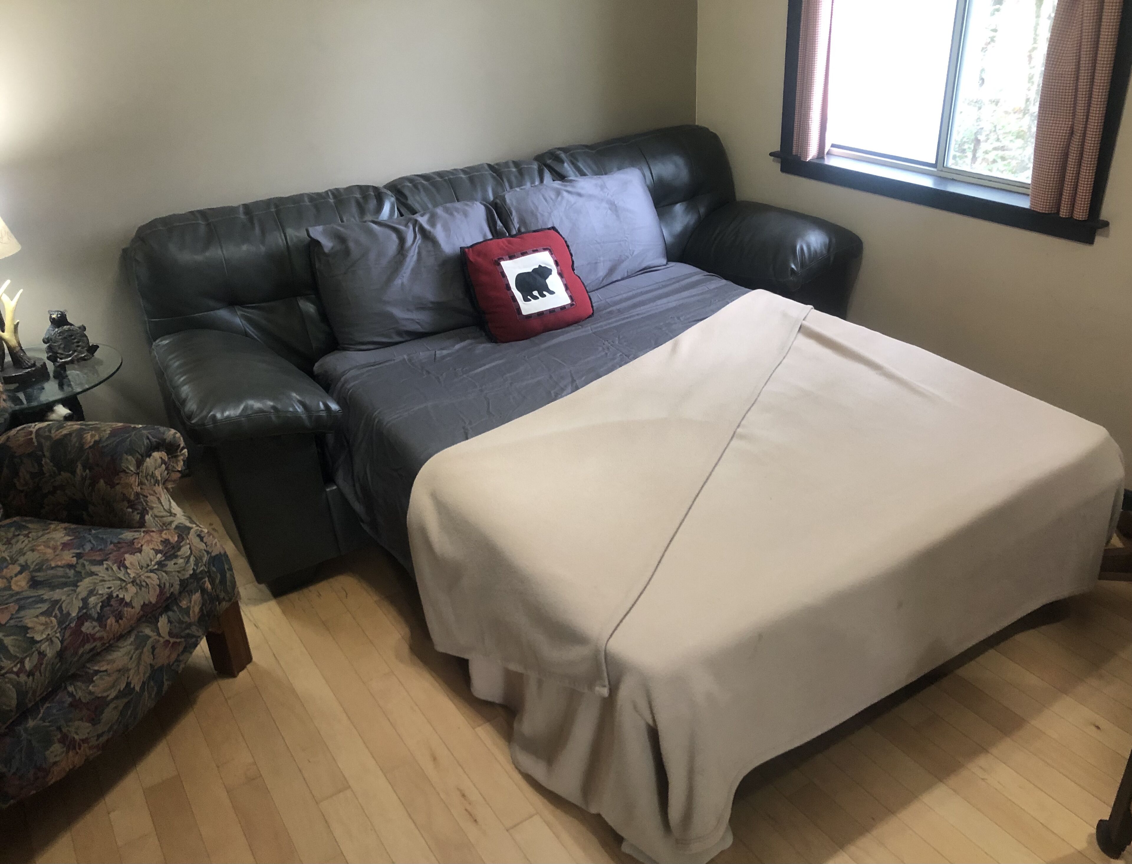 A bedroom with a bed, a sofa, a chair, and a window with curtains.