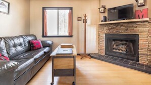 Una sala de estar con un sofá de cuero, una mesa de centro, una chimenea y un televisor.