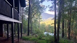 Una terraza de madera con vistas a un bosque y una montaña al fondo.