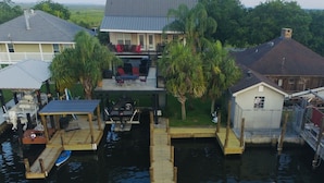 A wooden dock with two blue chairs, a small boat, and a covered area with a table and chairs. - Bayou Life Lodging, Charter Fishing, Ecotourism. Only 25 miles to French Quarter (Barataria)