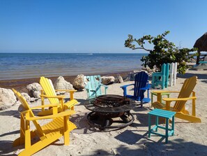 A beach setting with several Adirondack chairs, a fire pit, and a view of the ocean. - Oceanfront Property in Kawama Tower with Elevator, Lagoon and 2 Heated Pools (Key Largo)