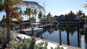 A marina with a docked boat, palm trees, and a wooden walkway. - Oceanfront Property in Kawama Tower with Elevator, Lagoon and 2 Heated Pools (Key Largo)