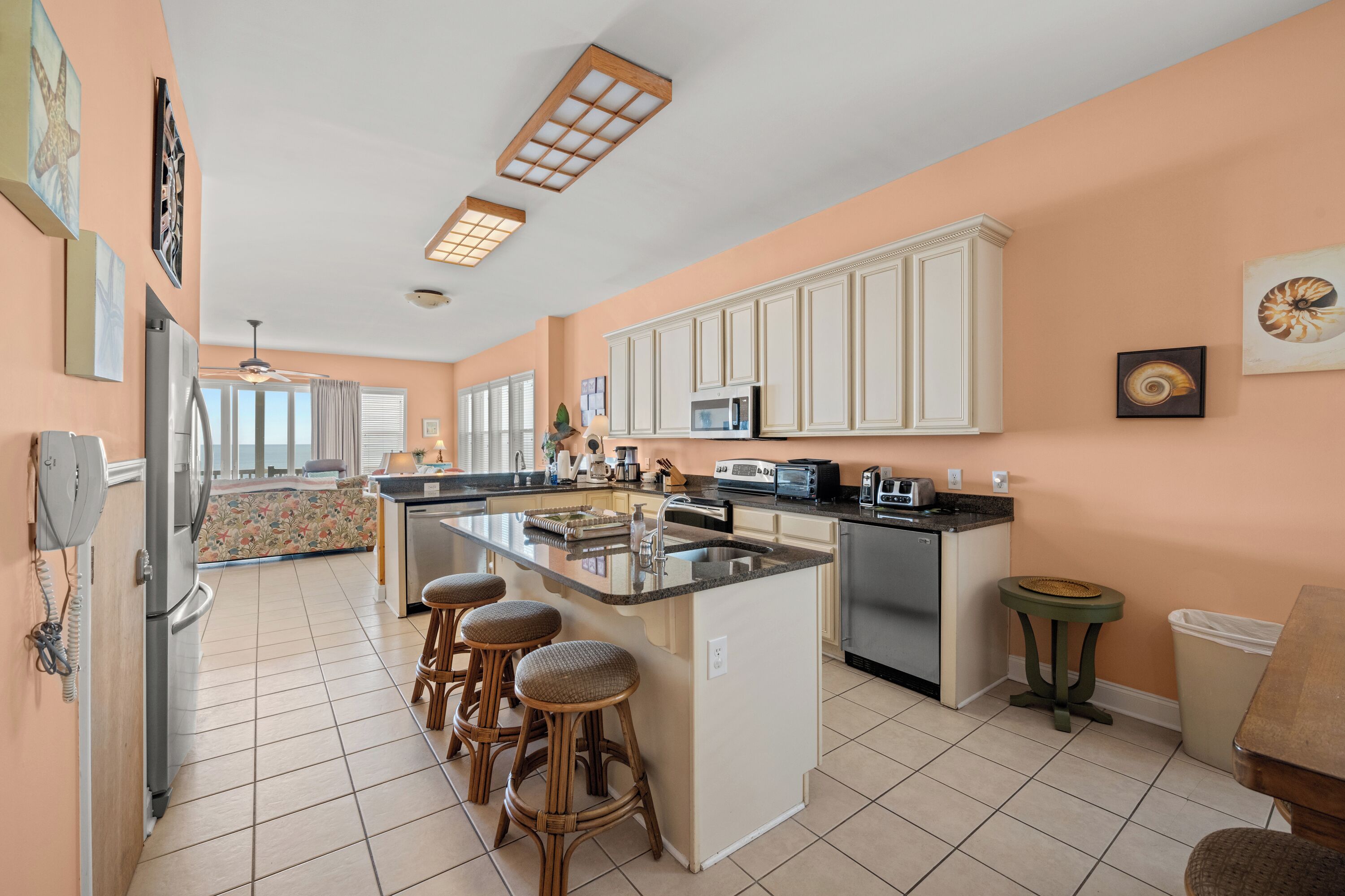 A spacious kitchen with a large island, white cabinetry, and a view to the living area.