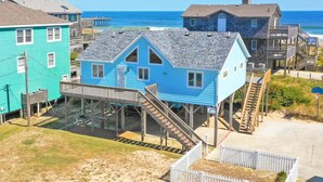 Una casa frente al mar con una terraza de madera y escaleras que bajan a la playa.