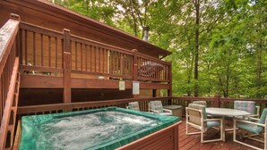 A wooden deck with a hot tub, chairs, and a table. - Jake's Hideaway (ellijay)
