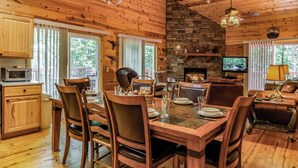A wooden cabin interior with a dining area, kitchen, and living room. - Jake's Hideaway (ellijay)