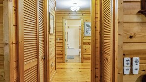 A wooden hallway with a ceiling light, wooden doors, and a view into a bathroom with a bathtub and toilet. - Jake's Hideaway (ellijay)