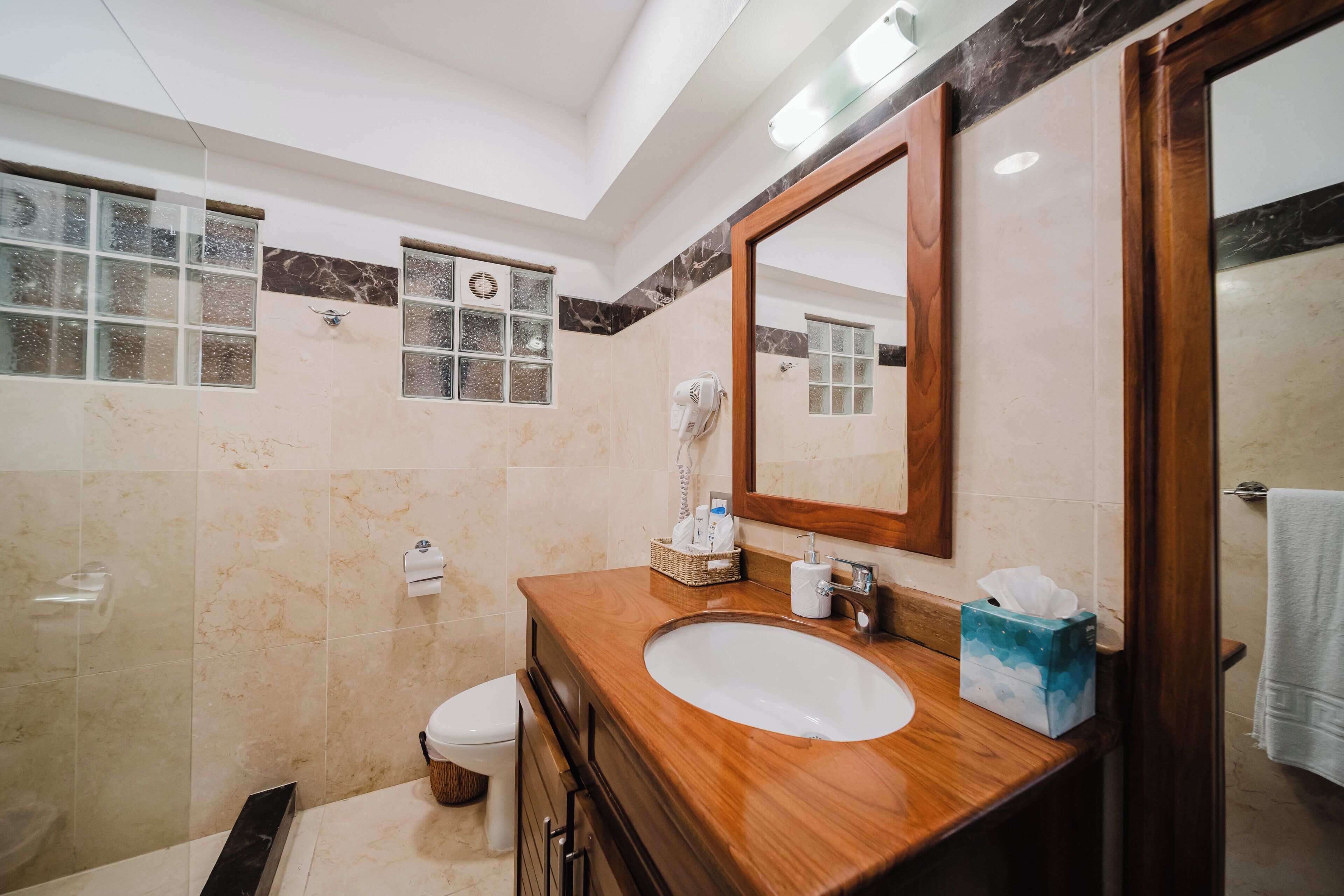 A bathroom with a wooden vanity, a large mirror, a white sink, and a glass shower enclosure.