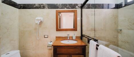 A bathroom with a toilet, sink, and shower area.