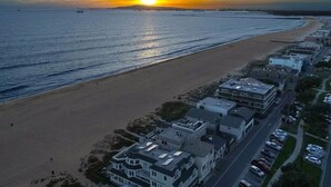 Un pueblo costero con una playa, casas y coches aparcados.