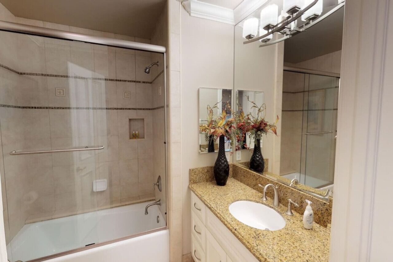 Une salle de bain avec une douche à parois de verre, un lavabo blanc et un grand miroir.