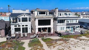 A beachfront property with a patio area, outdoor seating, and a view of the ocean. - ON THE SAND! Beachfront Huntington Beach 3bd home! Walk out of house on sand!! (Sunset Beach)