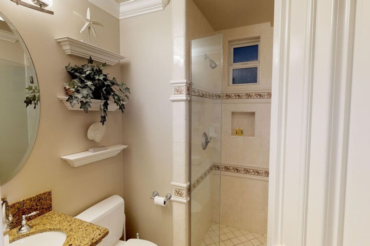 A bathroom with a toilet, sink, and shower area.