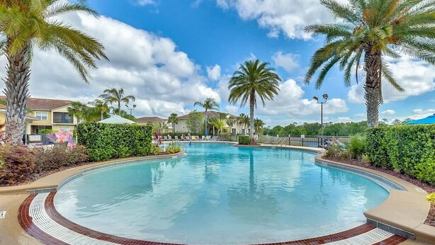 A large, circular swimming pool surrounded by palm trees and a well-maintained hedge. - Oakwater - Spacious 3BR 2.5BA townhome, gated (Kissimmee)