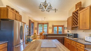 A kitchen with wooden cabinets, a stainless steel refrigerator, a wooden countertop, and a chandelier.
