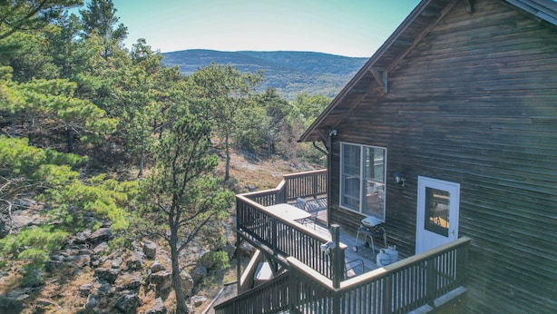 A wooden cabin with a balcony overlooking a mountainous landscape.