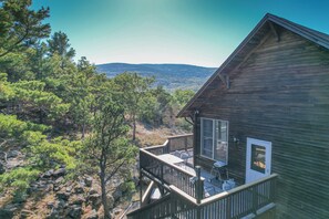 Une cabane en bois dotée d’un balcon donnant sur un paysage montagneux.