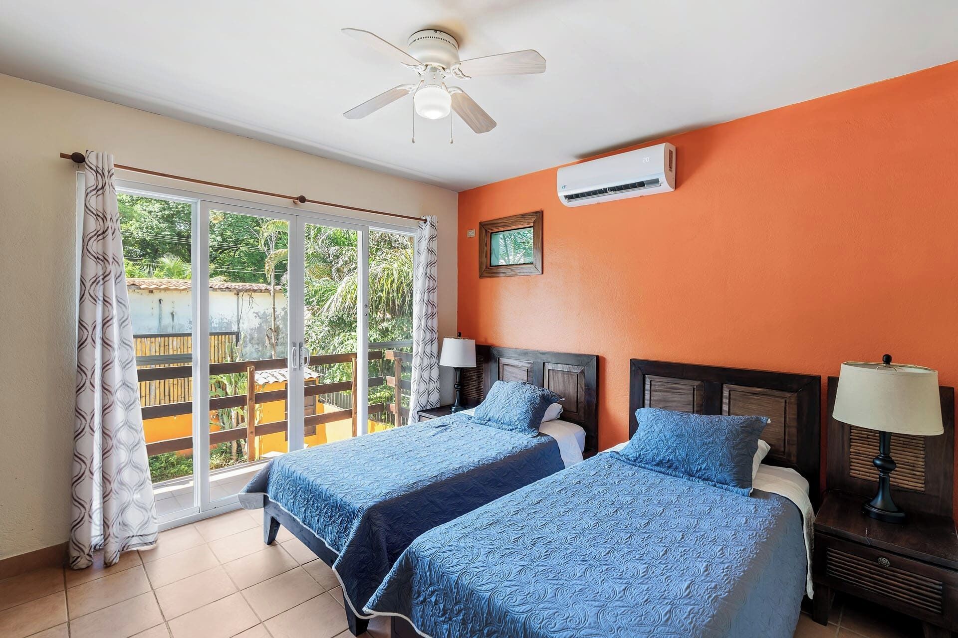 Habitación con dos camas, aire acondicionado, ventilador de techo y vistas al exterior.
