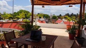 A covered outdoor seating area with a table, chairs, and a laptop. - 2 Blocks from ADO station + free bikes (Tulum)