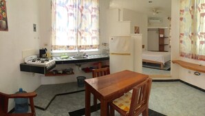 A compact hotel room with a kitchenette, a single bed, a small table, and a chair. - 2 Blocks from ADO station + free bikes (Tulum)