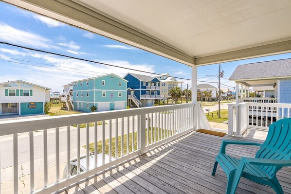 A covered porch with a view of a residential area, including a building with a sign that reads 'Turtle Cove.' - Fort Knox - Quaint 3 BR Home - Middle of the Island (Surf City)