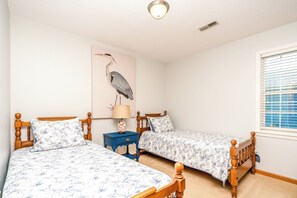 A bedroom with two wooden beds, a nightstand, a lamp, and a wall-mounted artwork. - What Time Is It? - Quaint 3 BR Home - Check in any day! (Surf City)
