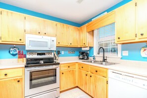 A kitchen with wooden cabinets, a microwave, stove, oven, coffee maker, and a dishwasher. - What Time Is It? - Quaint 3 BR Home - Check in any day! (Surf City)
