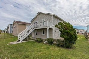 A two-story residential building with a front porch, a staircase leading to a balcony, and a well-maintained lawn. - Fort Knox - Quaint 3 BR Home - Middle of the Island (Surf City)