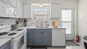 Una cocina moderna con electrodomésticos blancos, armarios grises y una ventana con vistas a la montaña.